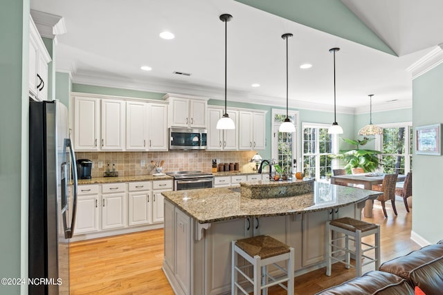 kitchen featuring decorative light fixtures, a kitchen island with sink, stainless steel appliances, and white cabinetry