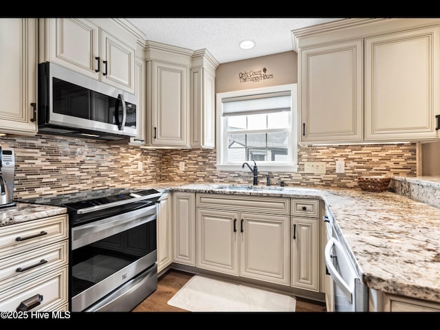 1204 Maple Ridge Rd, Wilmington, NC 28411 - kitchen with appliances with stainless steel finishes, cream cabinetry, decorative backsplash, light wood finished floors, and a textured ceiling