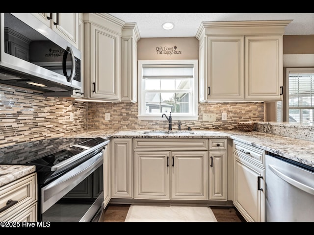 1204 Maple Ridge Rd, Wilmington, NC 28411 - kitchen featuring stainless steel appliances, tasteful backsplash, light stone countertops, cream cabinetry, and a textured ceiling