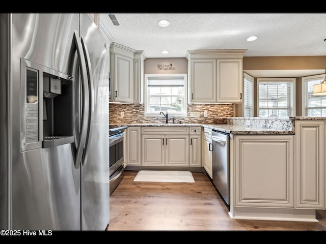 1204 Maple Ridge Rd, Wilmington, NC 28411 - kitchen with appliances with stainless steel finishes, a textured ceiling, light wood-style flooring, backsplash, and light stone counters