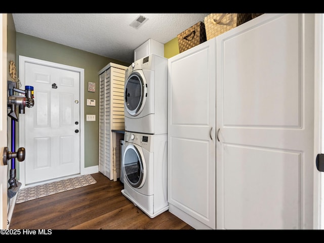 1204 Maple Ridge Rd, Wilmington, NC 28411 - washroom with estacked washer and dryer, dark wood-style flooring, a textured ceiling, and cabinet space