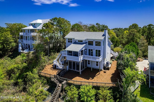 10002 Coast Guard Rd, Emerald Isle, NC 28594 - rear view of house with stairway, a sunroom, a chimney, a shingled roof, and a fenced backyard