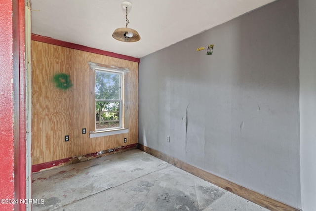 empty room with concrete flooring and wood walls