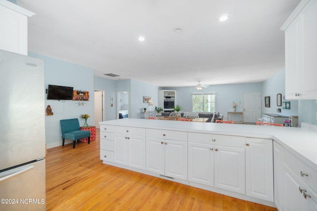 kitchen with white cabinetry, light wood-type flooring, stainless steel fridge, kitchen peninsula, and ceiling fan