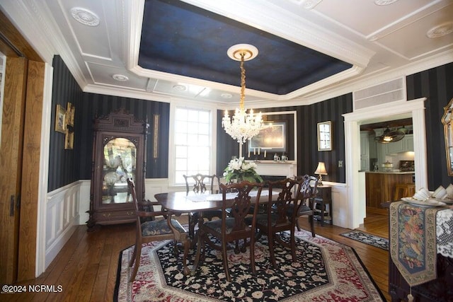 dining space with a chandelier, hardwood / wood-style flooring, a raised ceiling, and crown molding