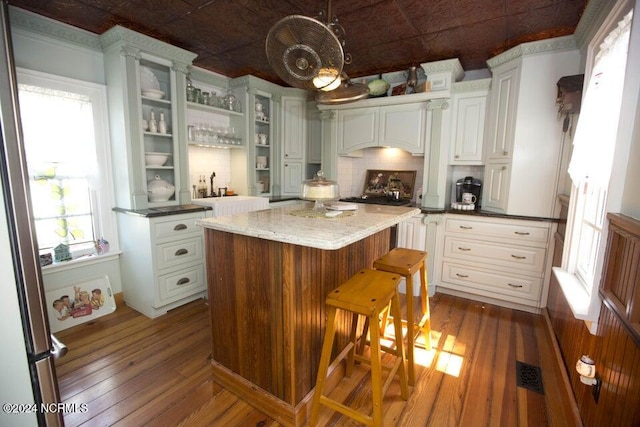 kitchen with white cabinets, dark hardwood / wood-style floors, a center island, and a kitchen bar