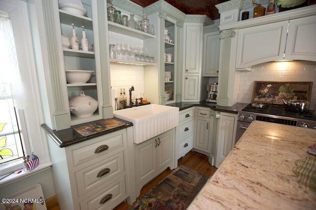 kitchen featuring white cabinetry, sink, tasteful backsplash, dark stone countertops, and stainless steel stove