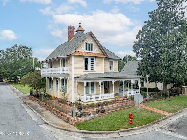 view of front facade with a balcony, covered porch, and a front yard