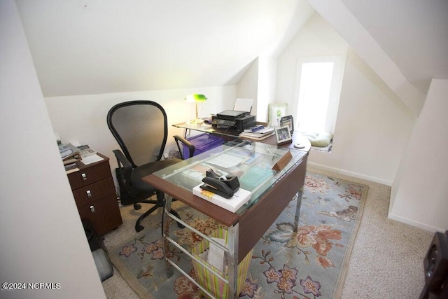 home office with lofted ceiling and light carpet