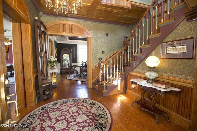 foyer with hardwood / wood-style floors, an inviting chandelier, coffered ceiling, crown molding, and beamed ceiling