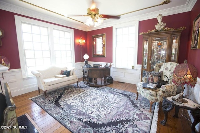 living area with hardwood / wood-style flooring, crown molding, and a healthy amount of sunlight