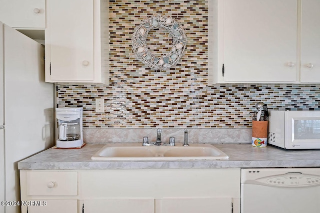 kitchen featuring white appliances, white cabinetry, sink, and backsplash