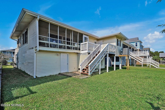 rear view of property featuring a sunroom, a lawn, and a wooden deck