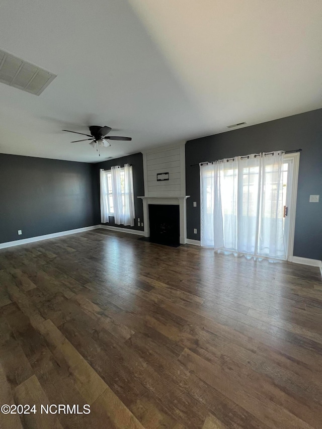 unfurnished living room featuring a fireplace, ceiling fan, and dark hardwood / wood-style flooring