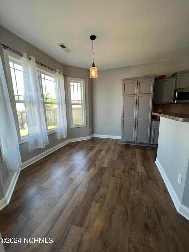 unfurnished dining area with a wealth of natural light and dark hardwood / wood-style flooring