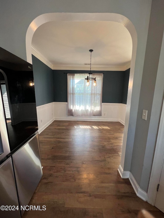 unfurnished dining area featuring an inviting chandelier, crown molding, and dark hardwood / wood-style flooring