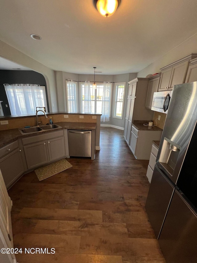 kitchen with stainless steel appliances, dark wood-type flooring, sink, gray cabinets, and decorative light fixtures