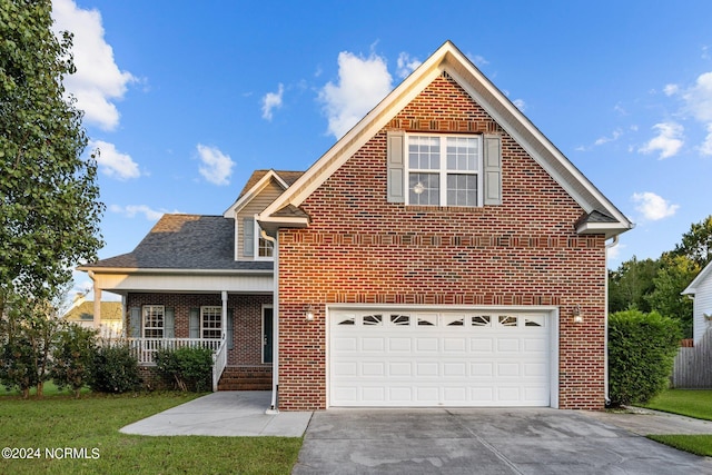 front of property featuring covered porch, a front yard, and a garage