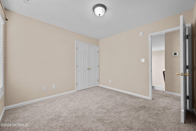 unfurnished bedroom featuring light carpet and a closet