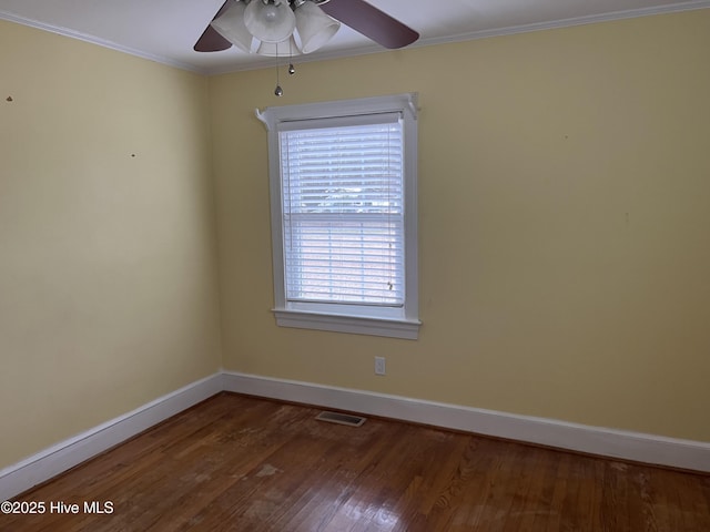 empty room with dark hardwood / wood-style flooring, crown molding, and a healthy amount of sunlight