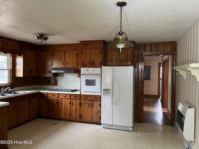 kitchen featuring white appliances, heating unit, wooden walls, sink, and decorative light fixtures