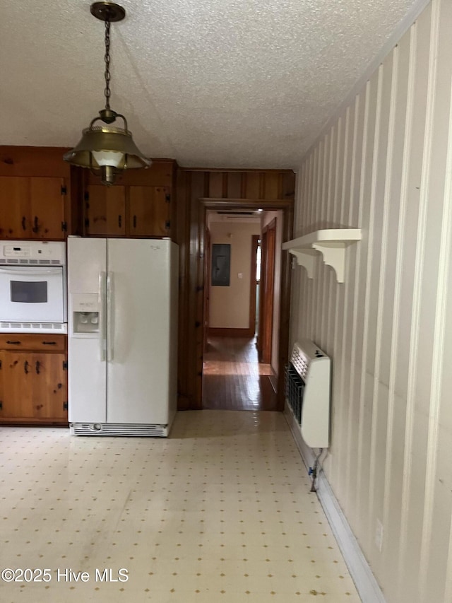 kitchen featuring a textured ceiling, white appliances, and heating unit