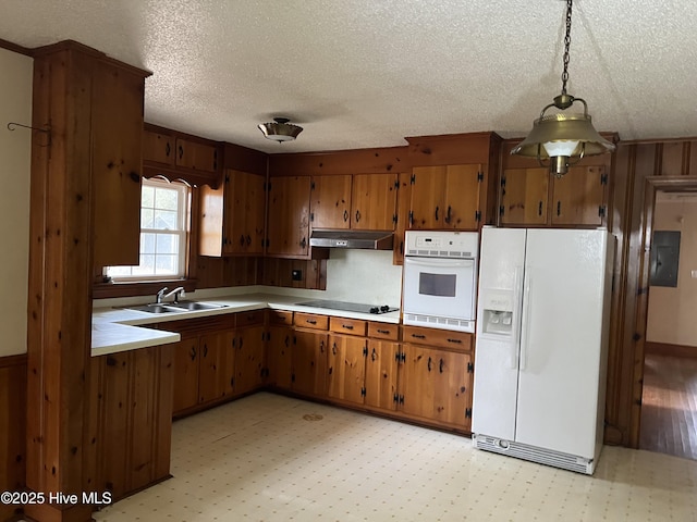 kitchen with decorative light fixtures, white appliances, sink, and wooden walls