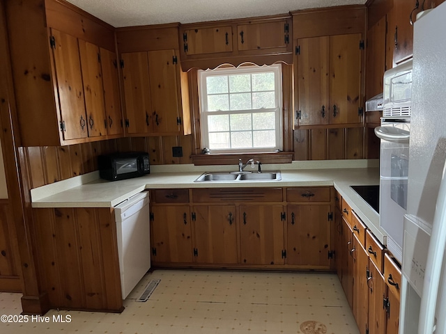 kitchen with black appliances, wood walls, sink, and a textured ceiling