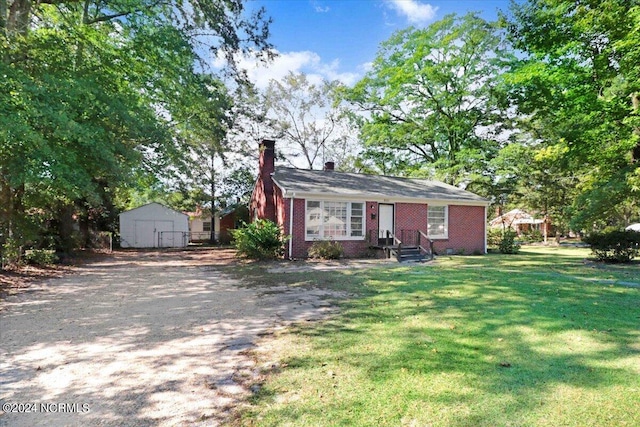 single story home featuring a front yard and a storage shed