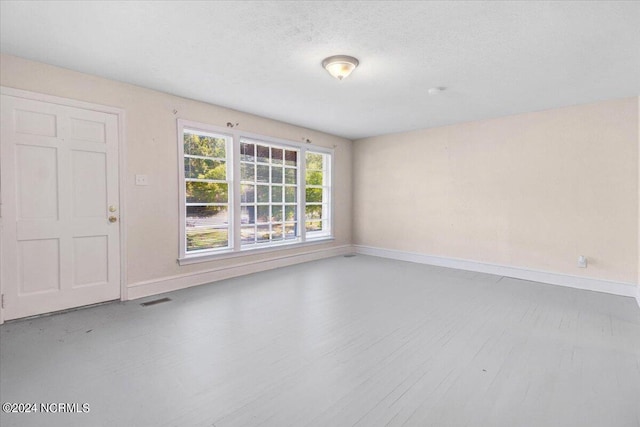 empty room featuring wood-type flooring and a textured ceiling