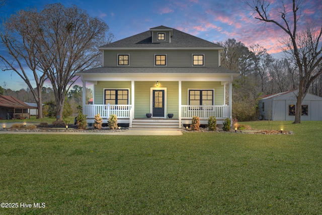 view of front of house featuring a porch, a front yard, an outdoor structure, and a shingled roof