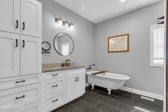 full bath with tile patterned flooring, visible vents, vanity, a freestanding bath, and baseboards