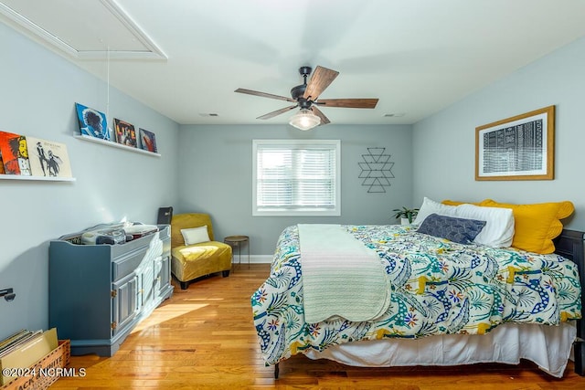 bedroom with attic access, visible vents, light wood-style flooring, and a ceiling fan