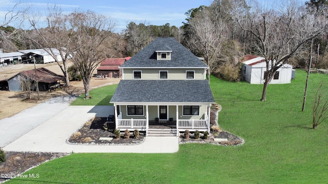 view of front of house featuring an outbuilding, a porch, a shingled roof, driveway, and a front lawn