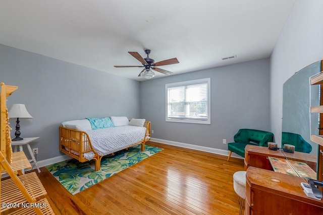 bedroom featuring a ceiling fan, visible vents, baseboards, and hardwood / wood-style flooring