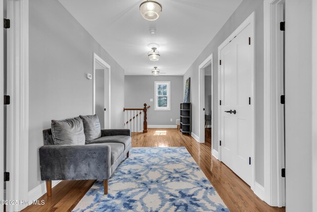 sitting room featuring light wood-type flooring, baseboards, and an upstairs landing