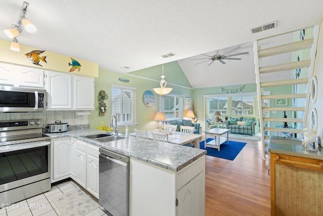 kitchen featuring kitchen peninsula, white cabinets, lofted ceiling, sink, and stainless steel appliances