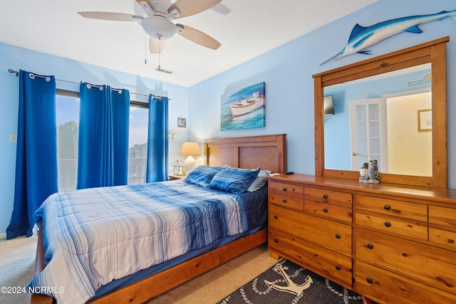 bedroom featuring ceiling fan, a textured ceiling, and light colored carpet