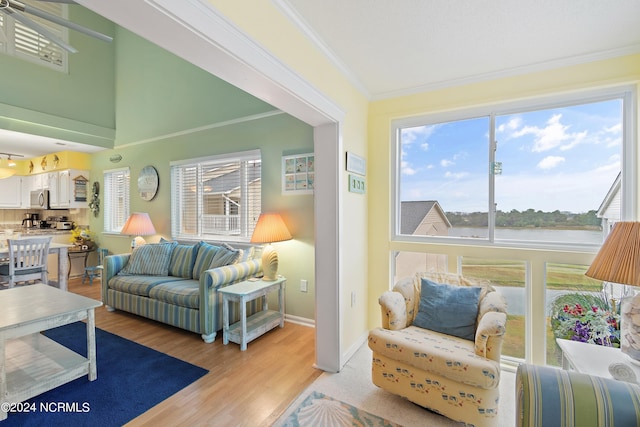 living room featuring light hardwood / wood-style flooring, a water view, and crown molding