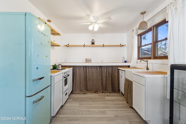 kitchen with hanging light fixtures, white appliances, white cabinets, and light hardwood / wood-style flooring