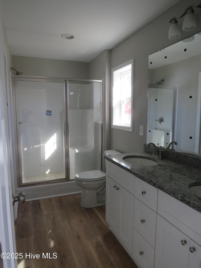 bathroom with hardwood / wood-style flooring, toilet, vanity, and walk in shower