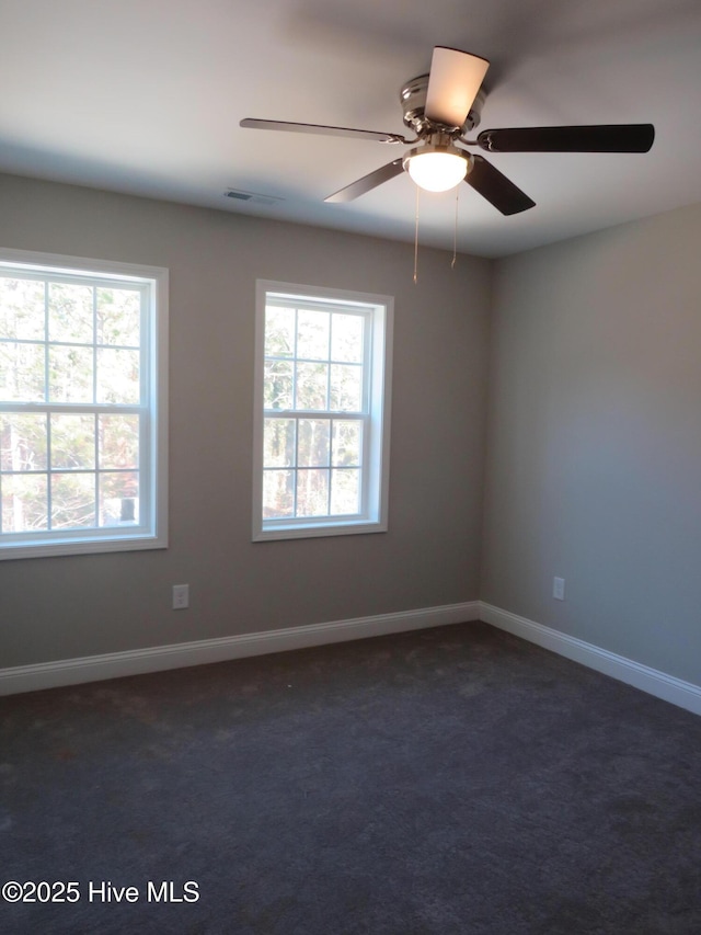 spare room with ceiling fan and dark carpet