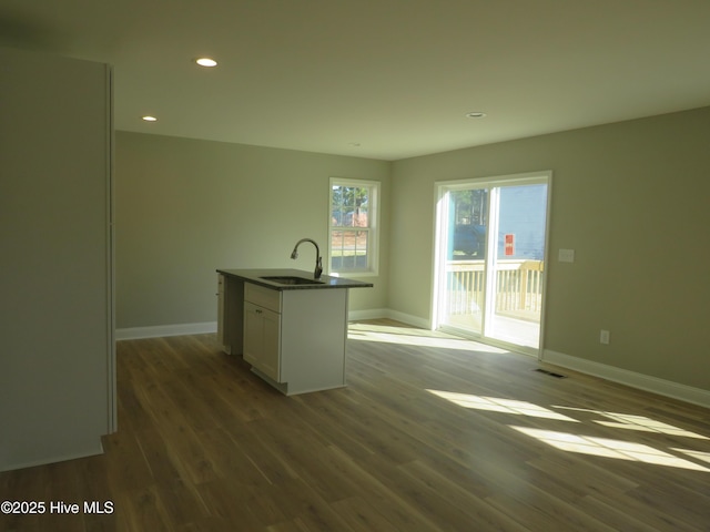 kitchen featuring a kitchen island with sink, sink, white cabinetry, and hardwood / wood-style floors