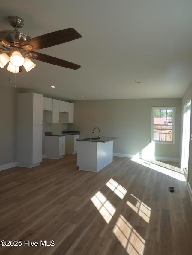 unfurnished living room featuring ceiling fan, hardwood / wood-style flooring, and sink