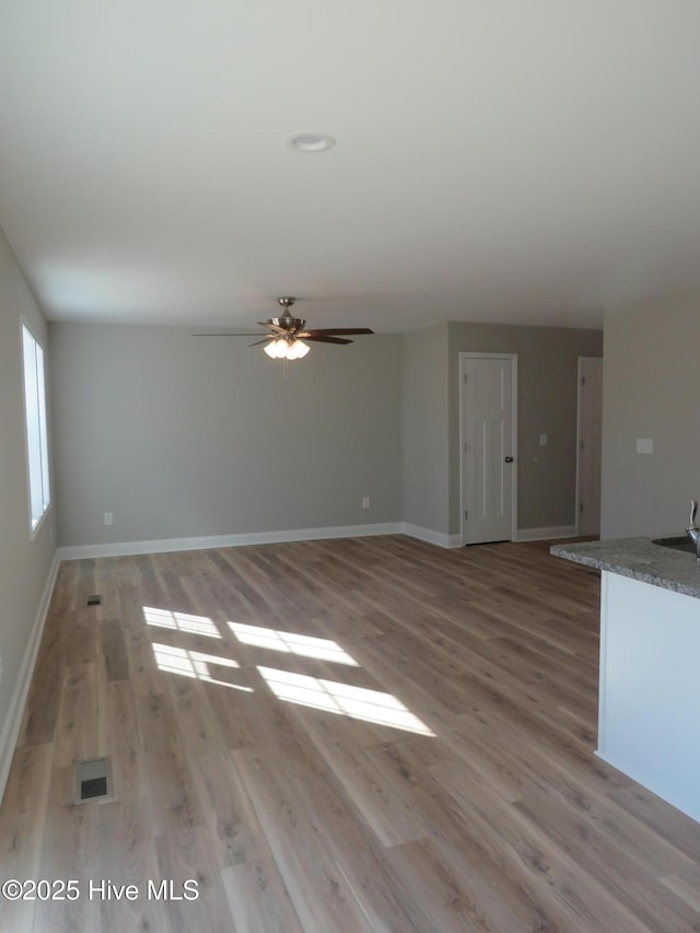 unfurnished living room with ceiling fan, sink, and light hardwood / wood-style flooring