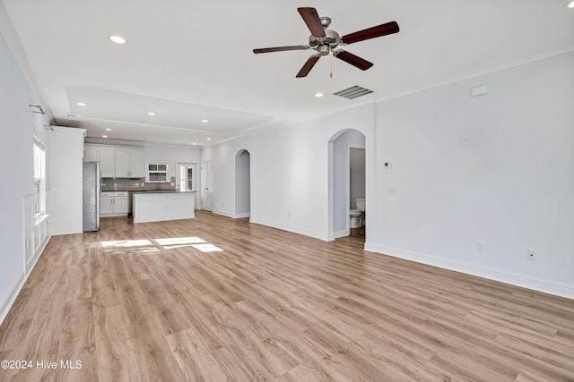 unfurnished living room with crown molding, sink, ceiling fan, and light hardwood / wood-style floors