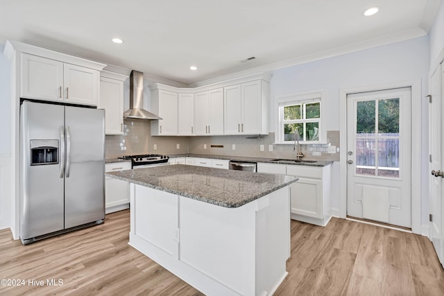 kitchen featuring stone counters, wall chimney range hood, sink, appliances with stainless steel finishes, and white cabinetry