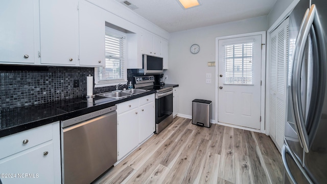 kitchen featuring backsplash, light wood-type flooring, appliances with stainless steel finishes, white cabinets, and a sink