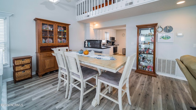 dining area with visible vents, baseboards, a high ceiling, and light wood-style floors