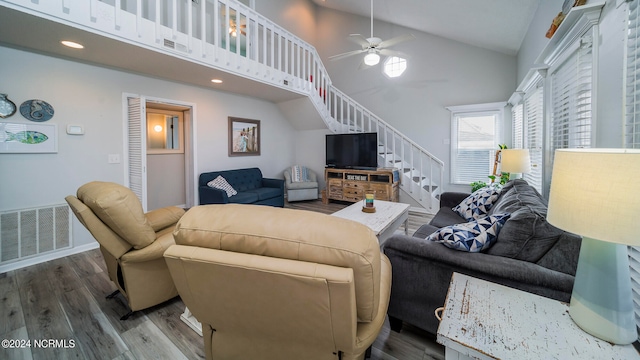 living room featuring visible vents, stairway, high vaulted ceiling, and wood finished floors